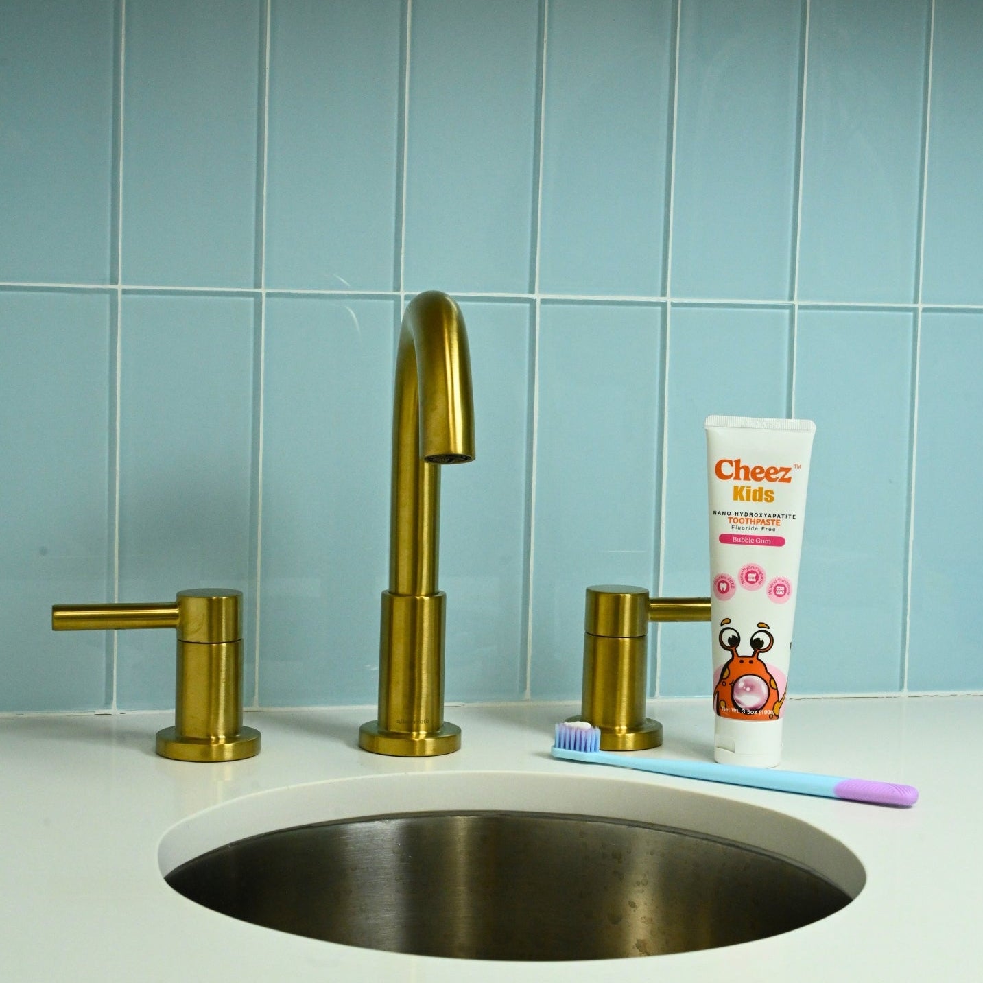 Cheez Kids bubble gum toothpaste next to toothbrush on bathroom sink